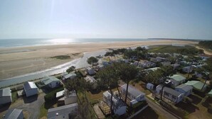 Een kustgebied met een strand, een kleine nederzetting met stacaravans, en een weg naar het strand.