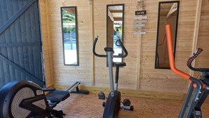 Un gimnasio con equipo de ejercicio, paredes de madera y un espejo grande.