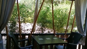 Un patio al aire libre con una mesa y sillas, rodeado por barandas de madera y un tapete estampado.