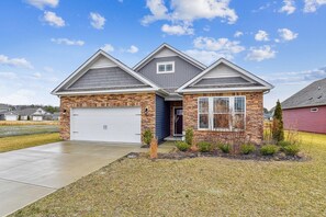 Una casa de dos pisos con fachada de piedra, garaje y césped bien cuidado.