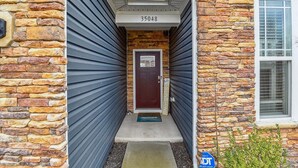 A house with a stone facade, a dark blue garage door, and a mailbox with a 'Hello Sunshine' sign. - Beach Club Getaway! Ample Amenities and Short Drive to Beaches! (OceanView)