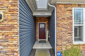 A house with a stone facade, a dark blue garage door, and a mailbox with a 'Hello Sunshine' sign. - Beach Club Getaway! Ample Amenities and Short Drive to Beaches! (OceanView)