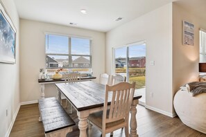 Un comedor con mesa y sillas de madera, vista a la playa y un ventanal grande.
