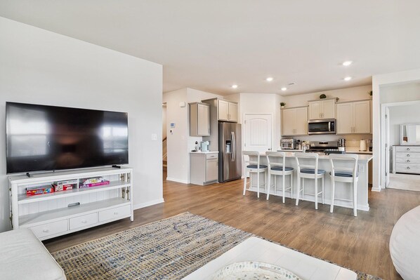 Una cocina moderna con gabinetes blancos, un refrigerador de acero inoxidable y un microondas.