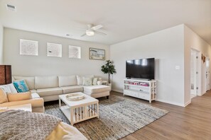 A living room with a sofa, coffee table, TV stand, and artwork on the wall.