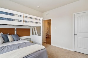 Un dormitorio con literas, una puerta y un pasillo que conduce a otra habitación.
