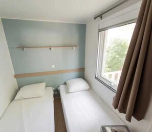 Cozy retreat with a single bed, bedside table, and window offering a view of the outdoors.