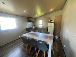 Uma cozinha compacta com mesa de jantar, cadeiras, micro-ondas e geladeira.