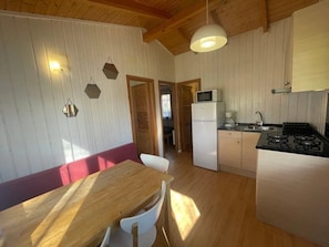 A kitchen with wooden cabinets, a microwave, a stove, and a dining area with a table and chairs.