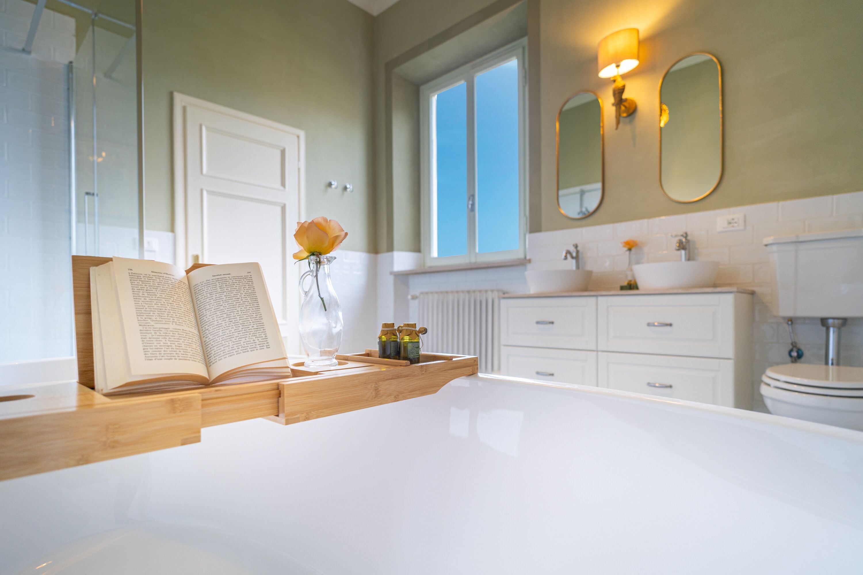 Ein modernes Badezimmer mit einer weißen Badewanne, einem hölzernen Waschtisch und einem großen Spiegel über dem Waschbecken.