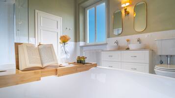 Ein modernes Badezimmer mit einer weißen Badewanne, einem hölzernen Waschtisch und einem großen Spiegel über dem Waschbecken.