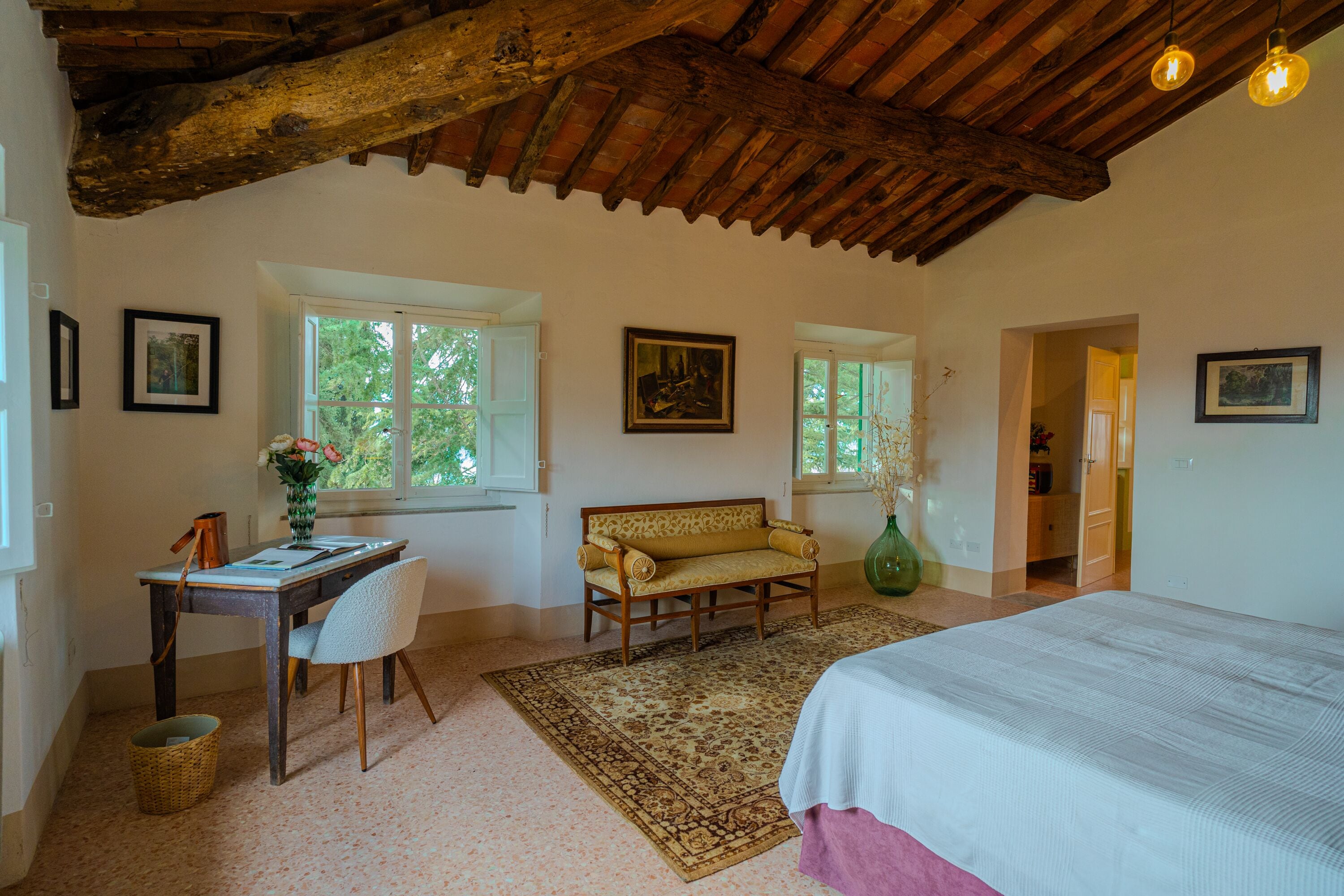 A bedroom with a bed, a sofa, a desk, and a window.