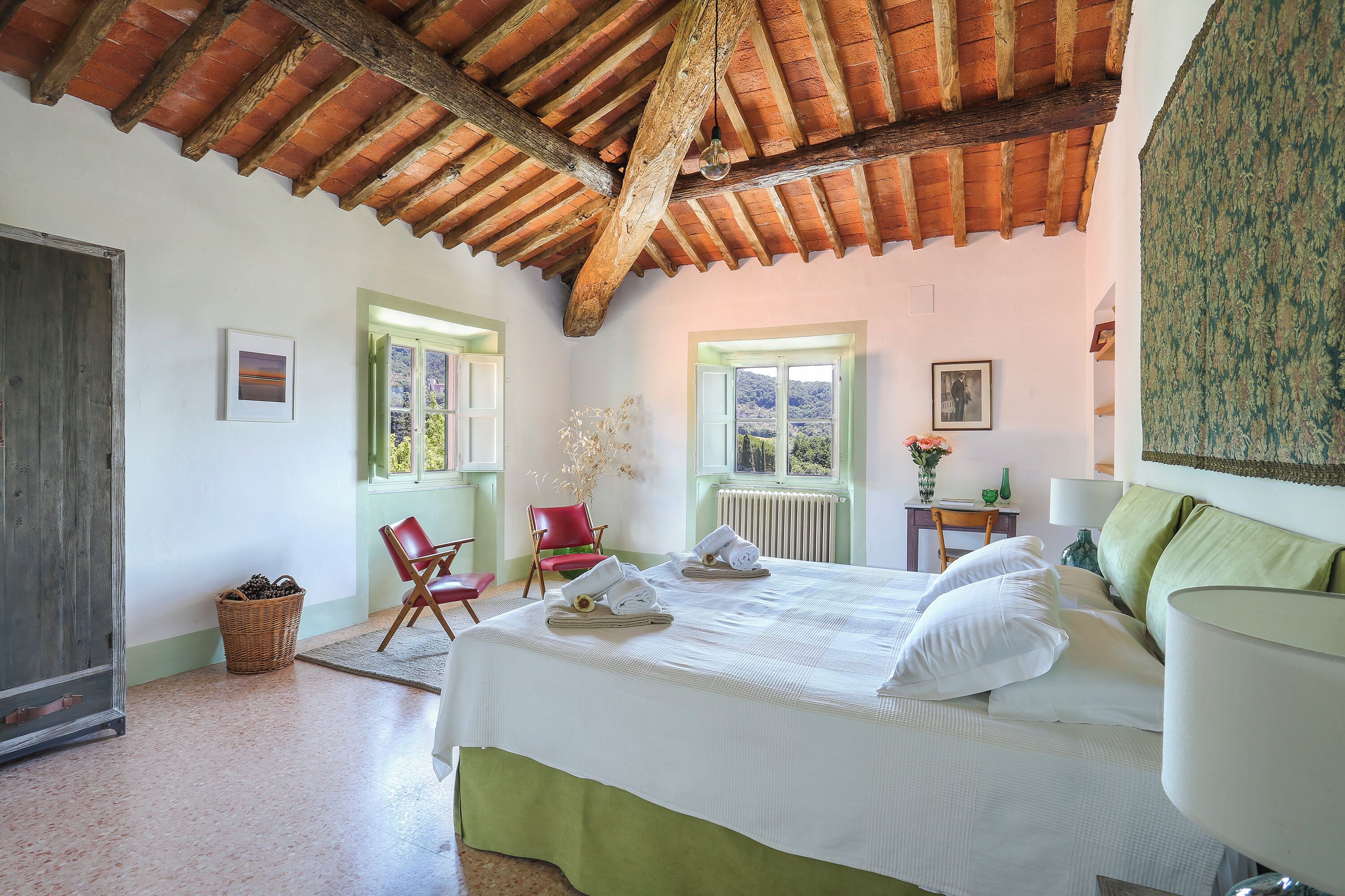 A bedroom with a bed, a chair, a small table, and a window with a view.