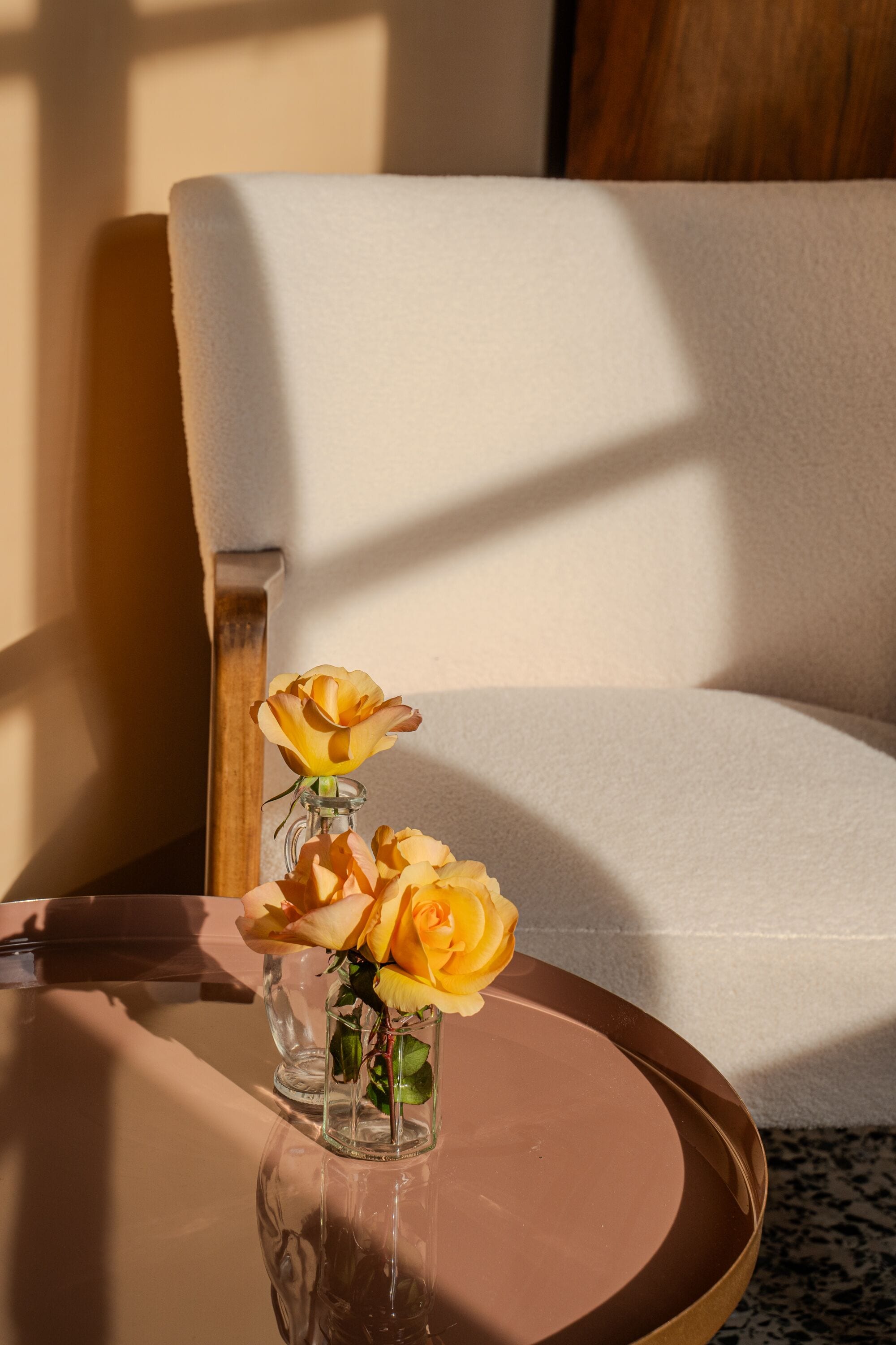 Un vase en verre contenant des roses jaunes, posé sur une table ronde.