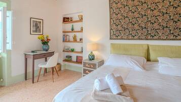 Un dormitorio con cama, escritorio, silla, mesita de noche y lámpara de pared.