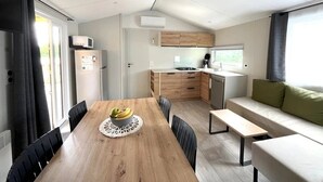 A compact living space with a dining table, a sofa, a kitchenette, and a window.