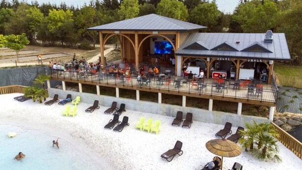 A beachside resort with a covered dining area, lounge chairs, and a pool.