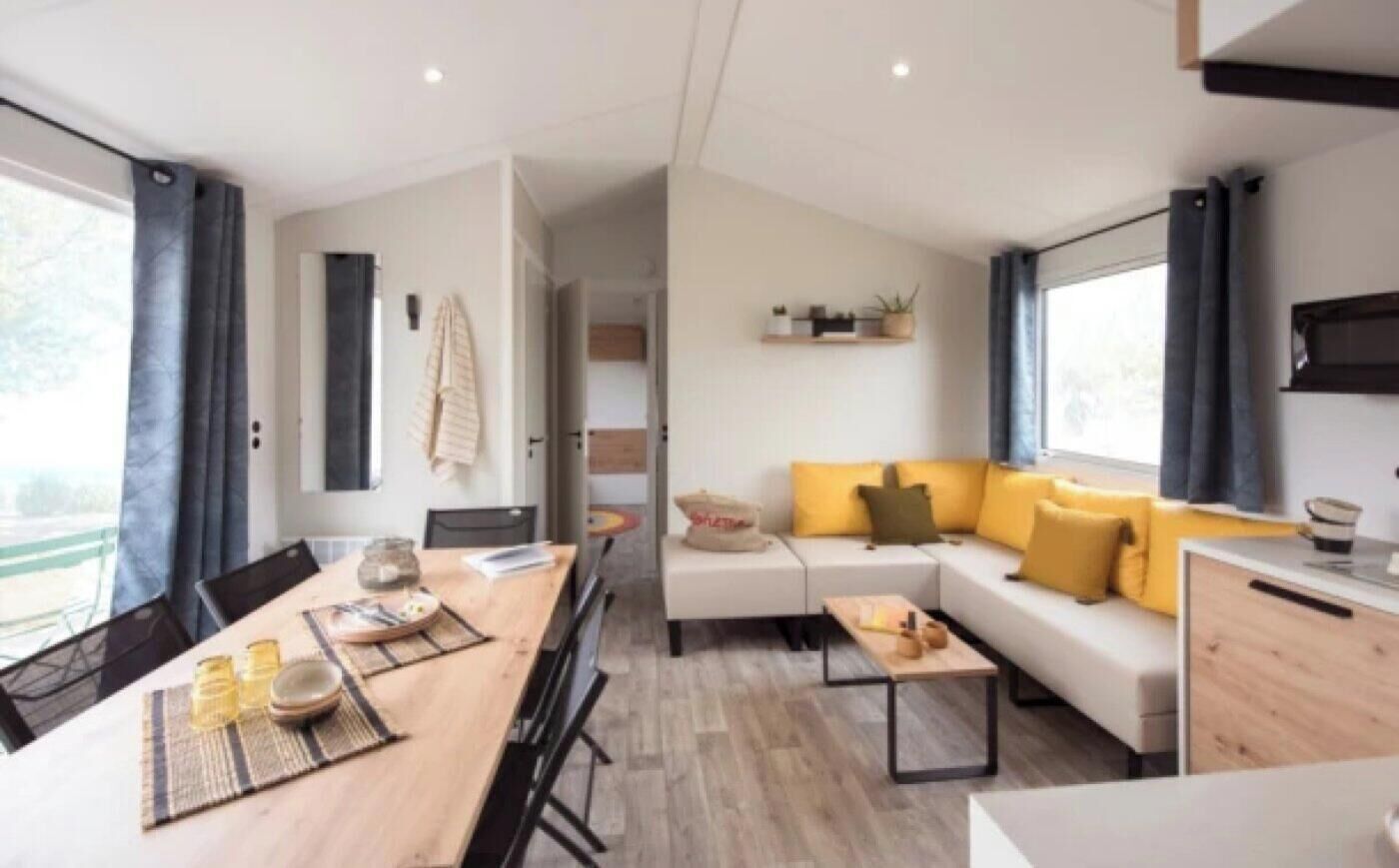 Un área de estar moderna y bien iluminada, con sofá, mesa de centro y mesa de comedor.