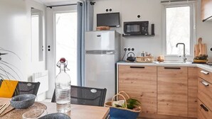 A compact kitchen with a microwave, refrigerator, and wooden cabinets.