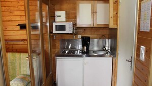 A compact kitchen with a microwave, coffee maker, and sink.