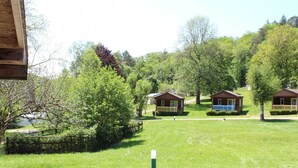 A row of cabins in a wooded area with a grassy field in the foreground.