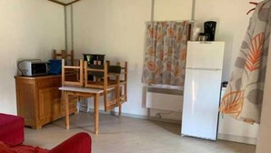 Une cuisine compacte équipée d’un four à micro-ondes, de chaises en bois, d’une table à manger et d’un réfrigérateur.