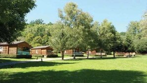 Une rangée de cabanes en bois, avec une pelouse verdoyante et des arbres en arrière-plan.