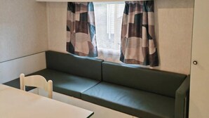 A compact kitchenette with a built-in stove, a small dining table, and a bench with a view through the window.