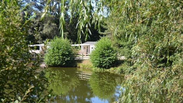 A serene riverside setting with a small house and a dock.