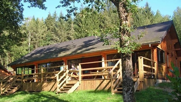 Une cabane en bois dotée d’un porche et d’un escalier menant à l’entrée.
