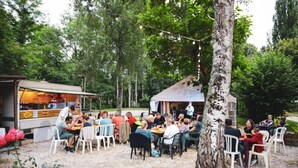 Un espace de restauration en plein air, avec des tables et des chaises, entouré d’arbres et agrémenté d’un camion-restaurant.