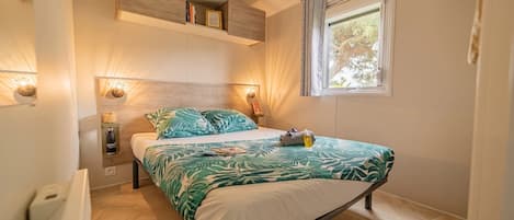 Une chambre à coucher comprenant un lit, une table de chevet, une étagère au-dessus du lit, une fenêtre avec des rideaux et des lampes fixées au mur.