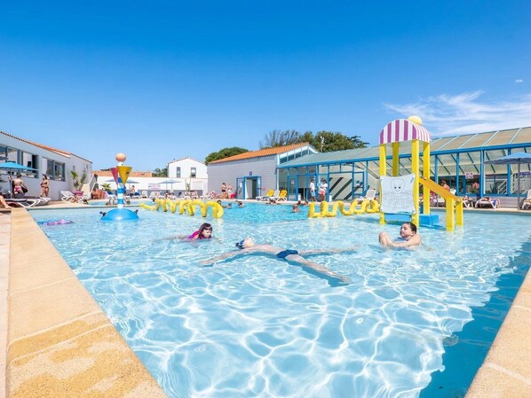 A swimming pool with inflatable toys, lounge chairs, and a clear blue sky.