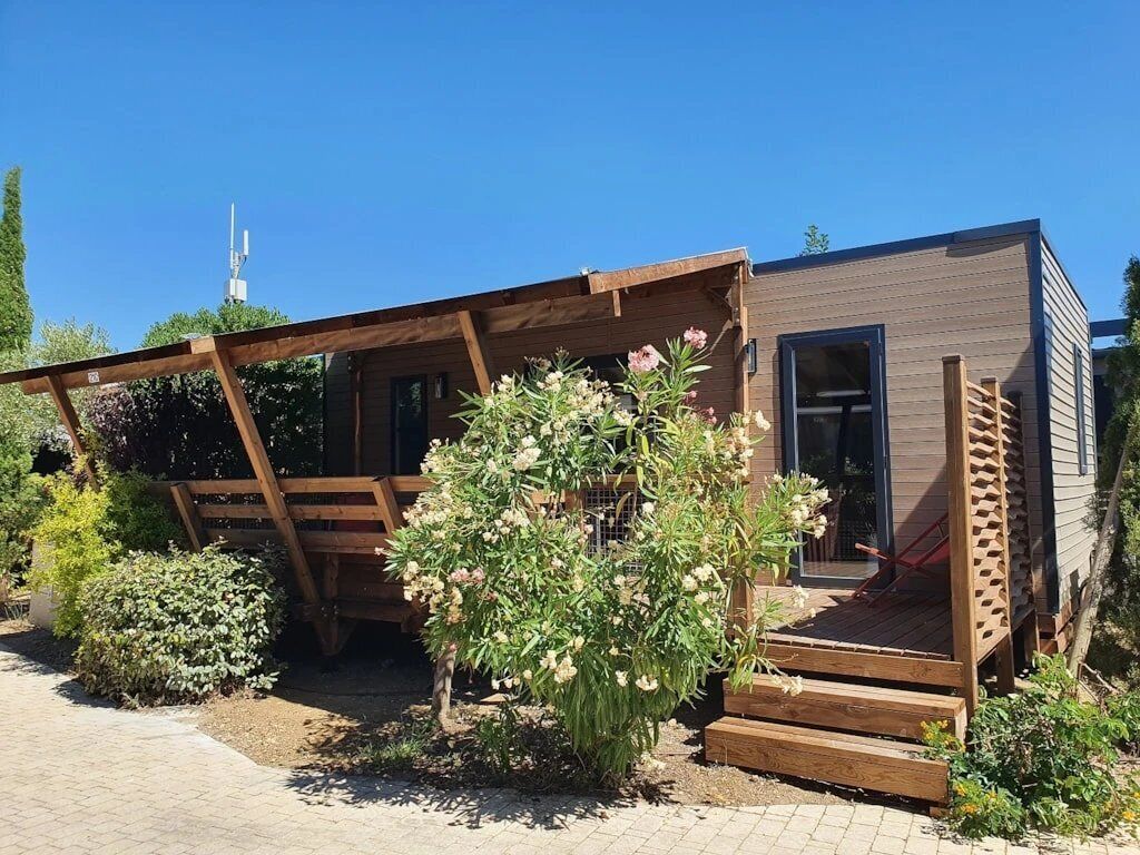 A modern cabin with a wooden deck, a covered porch, and a small garden area.