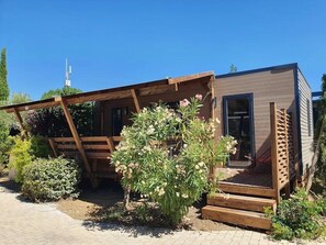 A modern wooden cabin with a covered porch and a small garden area.