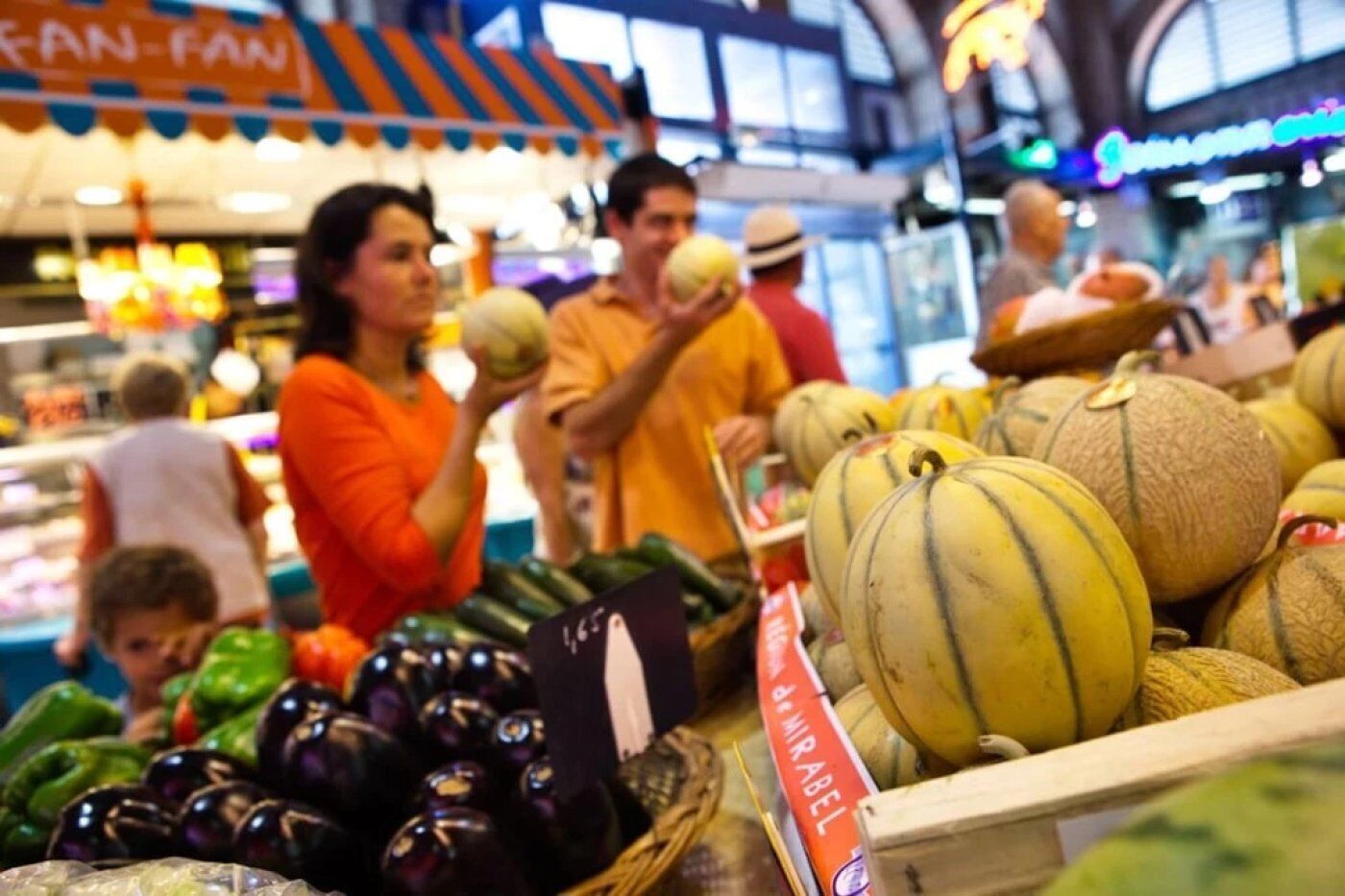 Een markt met diverse groenten en fruit, waaronder meloenen en aubergines.
