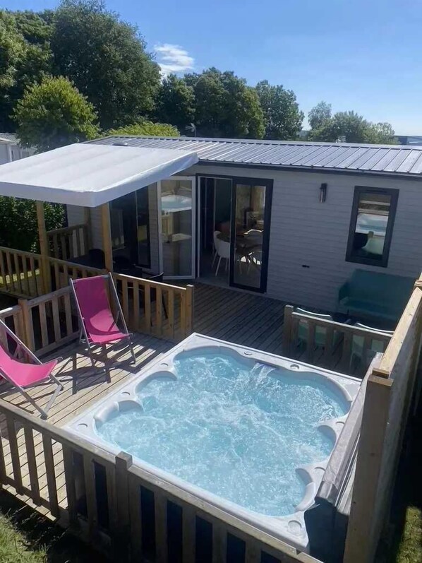 Relax in a hot tub area with a covered seating space and adjacent glass room.