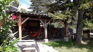 Een rustieke buitenruimte met een houten pergola, stenen muren en een hangmat.