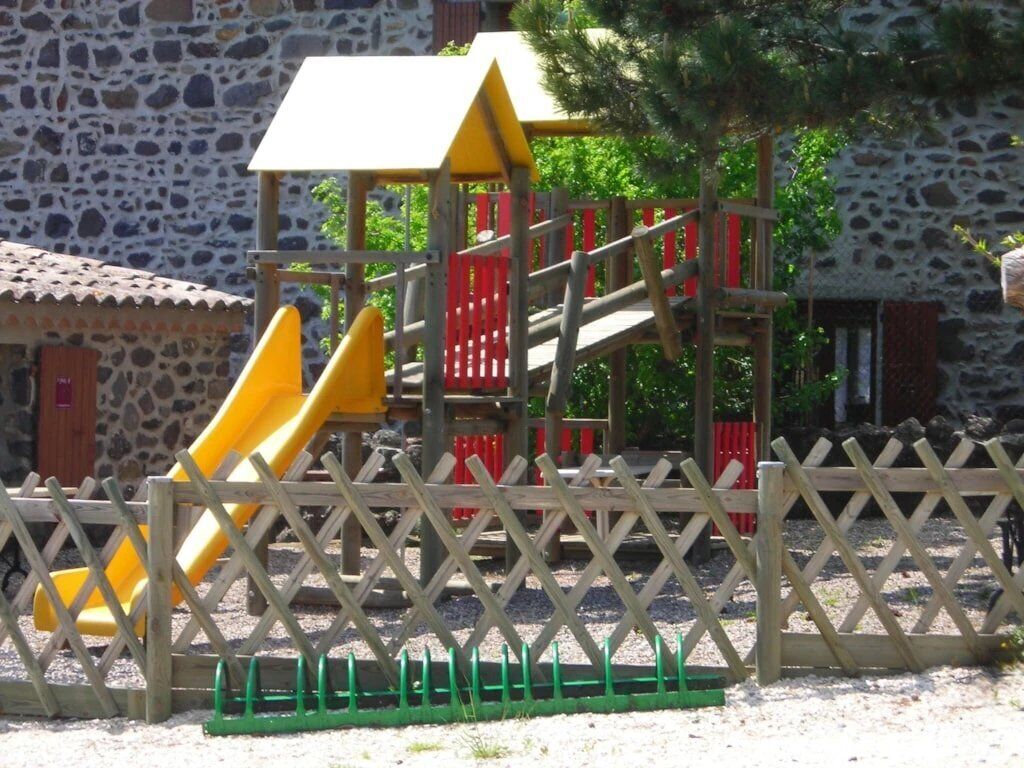 Een speeltuin met een gele glijbaan en een klimconstructie.