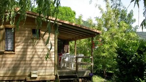 Una cabaña de madera con un porche, un ventanal pequeño y una puerta.