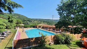 A swimming pool surrounded by lounge chairs and a forested hillside.