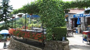 A restaurant with outdoor seating, a stone wall, and a sign reading "PLATS A EMPORT."