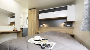 Un dormitorio moderno con cama, mesitas de noche, un espejo y almacenamiento integrado.