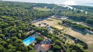 Vista aérea de una zona residencial con piscina, casas y un amplio campo abierto.