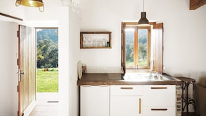 Una cocina con techo de madera, una ventana que da a zonas verdes y una lámpara colgante.