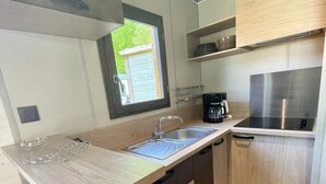 A modern kitchen with a central island, wooden cabinets, and a built-in stove. - ZEcamping 4 étoiles familial avec pataugeoire et jacuzzi (Coulon)