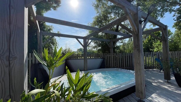 A wooden deck with a hot tub, surrounded by a wooden pergola and a wooden fence. - ZEcamping 4 étoiles familial avec pataugeoire et jacuzzi (Coulon)