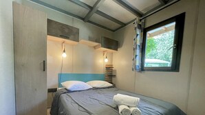 A bedroom with a bed, pillows, a window, and two wall-mounted lights. - ZEcamping 4 étoiles familial avec pataugeoire et jacuzzi (Coulon)