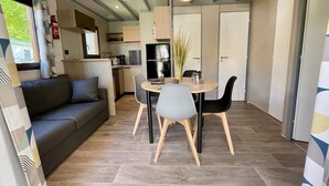 A compact living space with a kitchenette, a dining area with a table and chairs, and a sofa. - ZEcamping 4 étoiles familial avec pataugeoire et jacuzzi (Coulon)