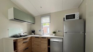 A modern kitchen with a gas stove, dishwasher, refrigerator, and a microwave.